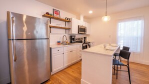 Una cocina moderna con electrodomésticos de acero inoxidable, muebles blancos y piso de madera.