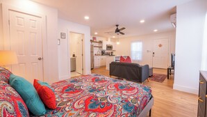 Un dormitorio con cama, sofá, mesa de comedor y cocina al fondo.