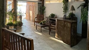 Een ruime binnenruimte met een houten bank, een bureau met een lamp en verschillende stoelen.