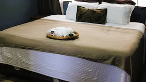 Een net opgemaakt bed met een mandje gevouwen handdoeken en een strak opgevouwen plaid.