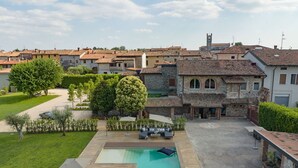 A residential area with a swimming pool, outdoor seating, and a stone building with a tower.