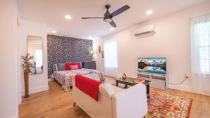 Ein modernes Schlafzimmer mit Bett, Fernseher, Deckenventilator und Wandairconditioner.