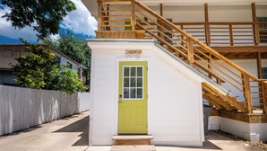 Ein Gebäude mit grüner Tür, einer Holztreppe und einer weißen Fassade.