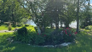 Um jardim com lago, rodeado por árvores e diversas plantas.