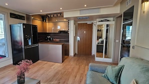 A compact living space with a kitchenette, a dining area, and a bedroom with a sliding door. - Charming 2-bedroom apartment with big Terrace , view of Eiffel Tower and Paris (Courbevoie)