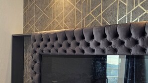A modern bedroom with a tufted headboard, a flat-screen TV, and a geometric-patterned wall. - Charming 2-bedroom apartment with big Terrace , view of Eiffel Tower and Paris (Courbevoie)