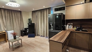 A modern kitchen with wooden cabinets, a built-in refrigerator, and a coffee machine. - Charming 2-bedroom apartment with big Terrace , view of Eiffel Tower and Paris (Courbevoie)