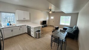 A spacious kitchen with white cabinets, a dining area with a table and chairs, a ceiling fan, and a large window providing natural light. - 404 Spacious 3 Bed 2 Bath Townhouse (Iowa City)