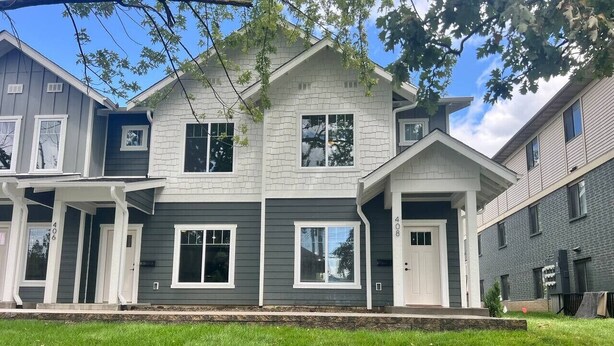 A two-story house with a front porch, a garage, and a well-maintained lawn. - 404 Spacious 3 Bed 2 Bath Townhouse (Iowa City)