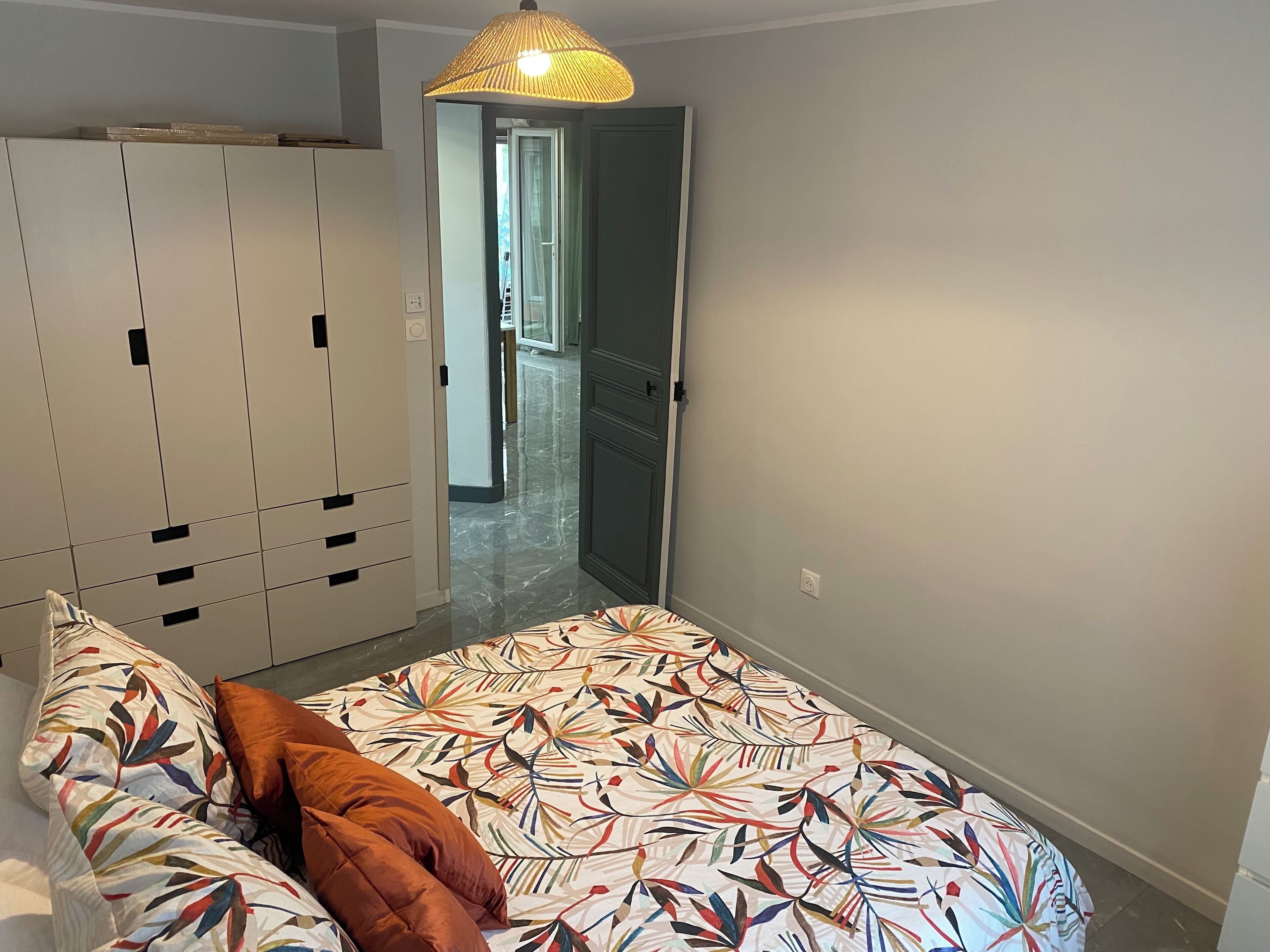 Une chambre à coucher comprenant un lit, une armoire et une porte donnant sur un couloir.
