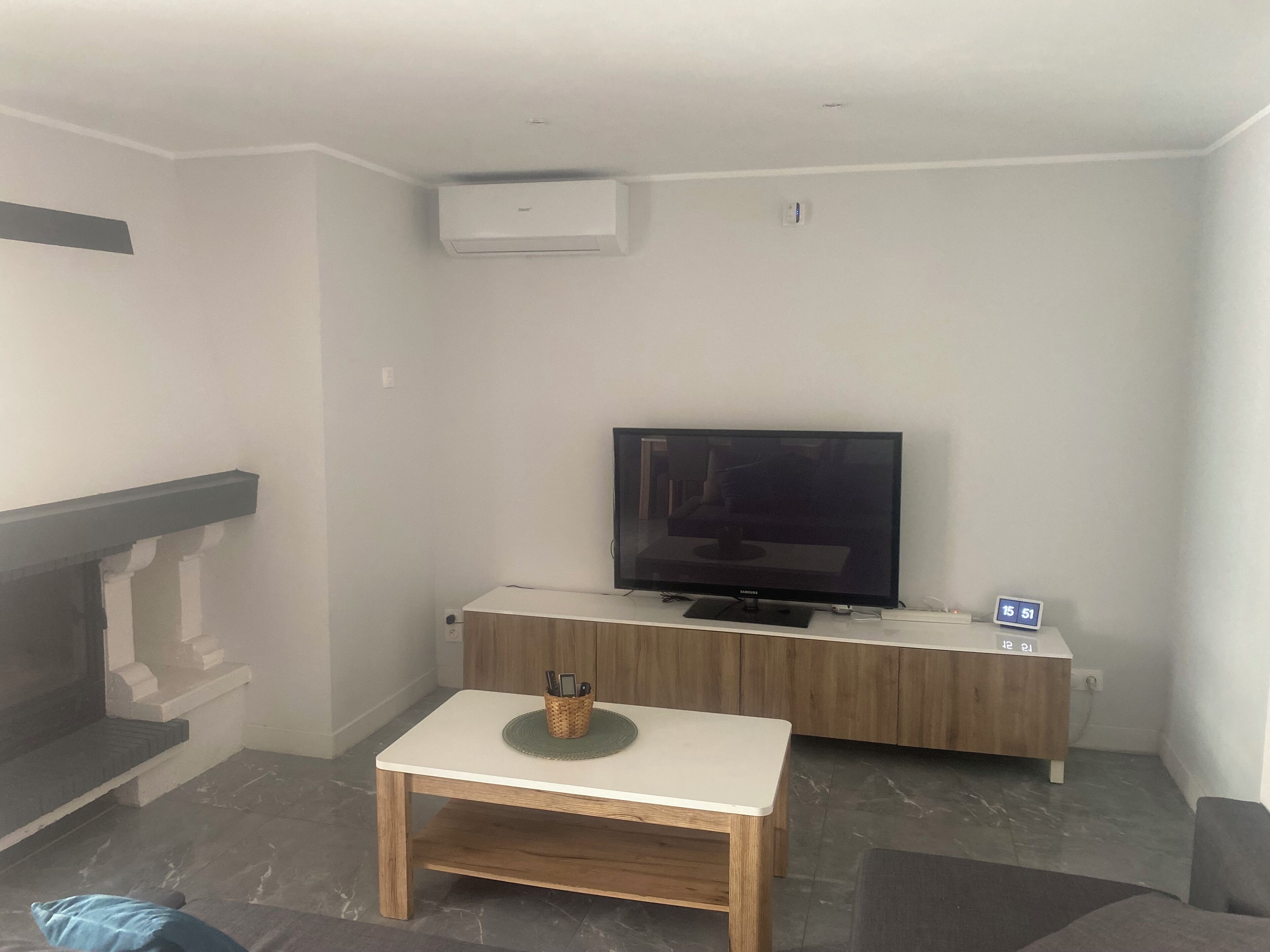 Een woonkamer met een flatscreen televisie, een klein tafeltje en een open haard.