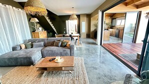En moderne stue med en hjørnesofa, et sofabord og et spiseområde med en trappe.