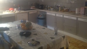 Una cocina con una mesa de comedor, sillas y un reloj en la pared.