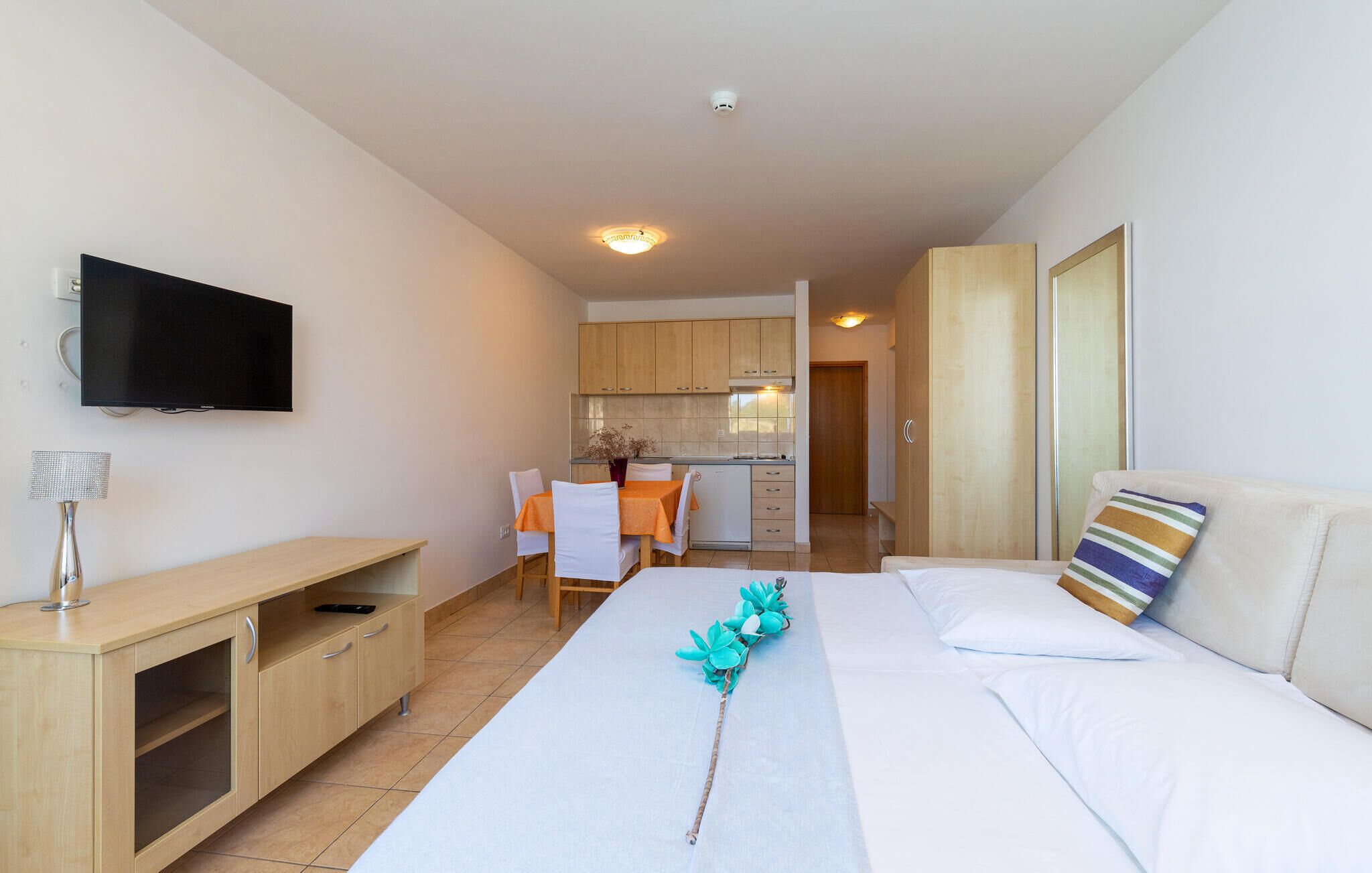 Une chambre d’hôtel équipée d’un lit, d’une télévision, d’un bureau, d’une kitchenette et d’une salle de bain.