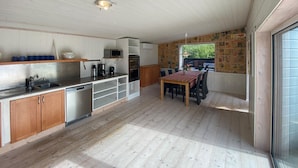 Una cucina compatta con mobili in legno, lavastoviglie, forno a microonde e zona pranzo con tavolo e sedie.