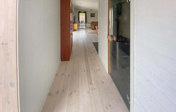 A narrow hallway with wooden flooring and white walls.