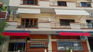 Un edificio de varios pisos con balcones, unidades de aire acondicionado y un coche estacionado en la calle.