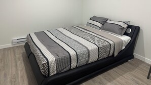 Une chambre à coucher moderne avec un cadre de lit en métal noir, une couvre-lit à motifs et une petite table de chevet.