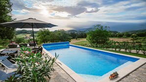 Una piscina amb terrassa de pedra, envoltada de vegetació i un viñedo.