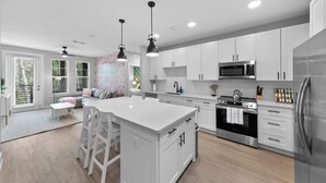 Een moderne keuken met witte kasten, roestvrijstalen apparatuur en hanglampen.