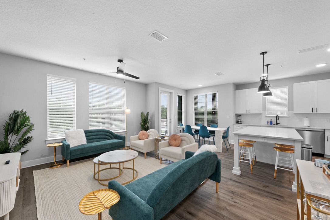 A modern living room with a sofa, chairs, a coffee table, and a dining area with a bar.