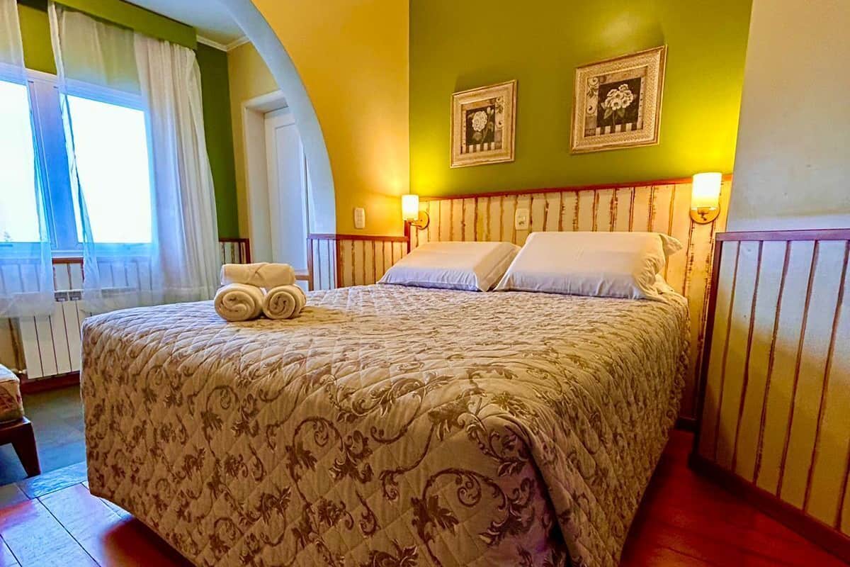 A bedroom with a bed, a window with curtains, and two wall-mounted lamps.