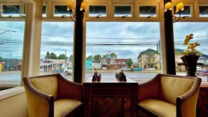 Una habitación con dos sillas, una mesa y vistas a una calle con edificios y coches.
