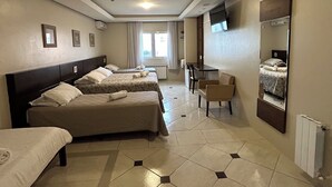 Habitación de hotel con dos camas, un escritorio, una silla, un espejo grande y una ventana con cortinas.