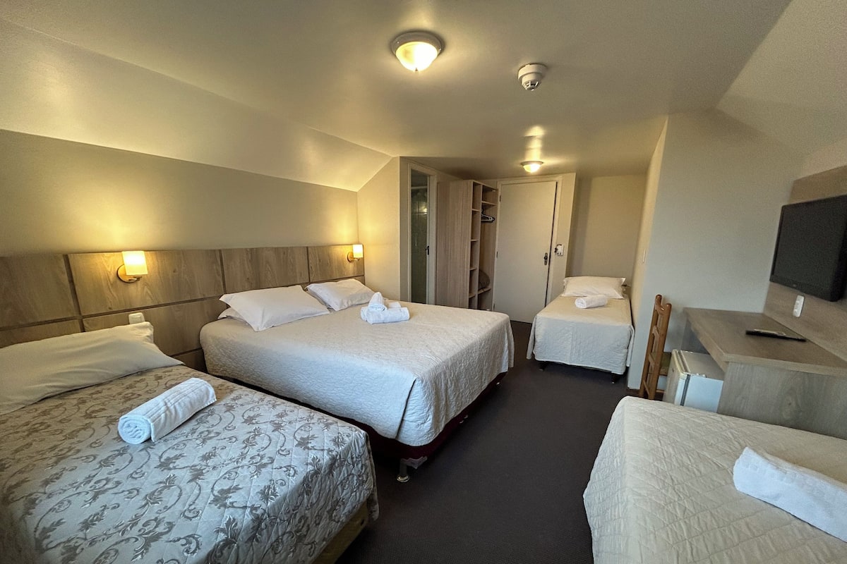 A hotel room with two beds, a desk, a TV, and a wardrobe.
