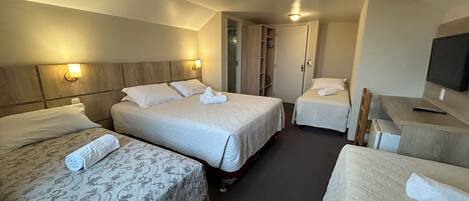 A hotel room with two beds, a desk, a TV, and a wardrobe.