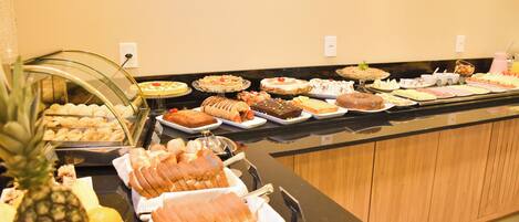 A buffet with various food items including fruits, pastries, and desserts.