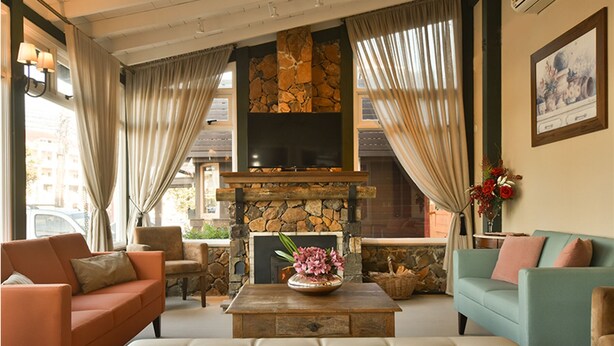 Una sala de estar acogedora con chimenea de piedra, asientos cómodos y un ventanal con cortinas.