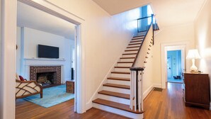Eine Treppe mit Holzstufen und einer Handläufe, die zu einem Raum mit Kamin und Wandfernseher führt.