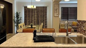 Cocina moderna con una isla central, pileta de acero inoxidable e iluminación colgante.