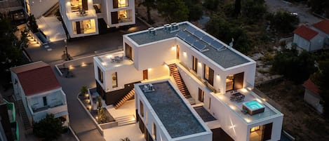 A modern multi-story residential building with a rooftop pool and solar panels.