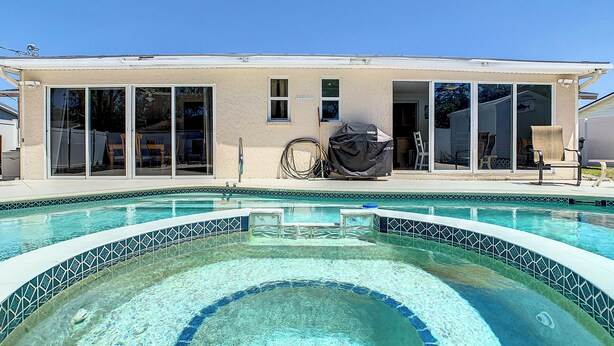 A house with a swimming pool, large sliding glass doors, and a covered grill.
