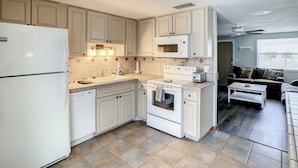 A compact kitchen with white cabinets, a microwave, an oven, and a refrigerator.