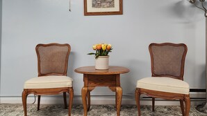 A room with two wicker chairs, a small wooden table with a vase of flowers, a framed picture on the wall, and a floor lamp. - Cozy Basement Apartment in Columbia  (Columbia)