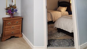 A bedroom with a bed, a dresser, a mirror, and a door leading to another room. - Cozy Basement Apartment in Columbia  (Columbia)