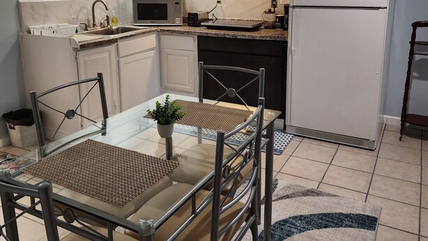 A compact kitchen with a dining area, featuring a microwave, stove, and refrigerator. - Cozy Basement Apartment in Columbia  (Columbia)