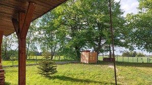 Un espace extérieur abrité doté d’une structure en bois, d’un petit arbre et d’un terrain clôturé.