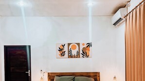 Un dormitorio con una cama de madera, una mesita de noche con lámpara, aire acondicionado de pared y una puerta.