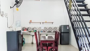 Una cocina compacta con una mesa de comedor, sillas, un refrigerador y un dispensador de agua.