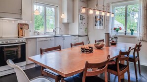 Una cocina moderna con armarios blancos, una mesa de comedor de madera y un horno empotrado.