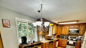Cozinha com armários de madeira, uma mesa de jantar e um candelabro.