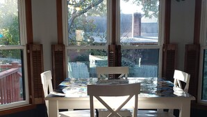 A dining area with a table and chairs, large windows, and a hanging plant. - Vacation home just 21 minutes from Historic Beale Street and Graceland (Memphis)