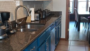 A kitchen with blue cabinets, a granite countertop, and a stainless steel sink. - Vacation home just 21 minutes from Historic Beale Street and Graceland (Memphis)