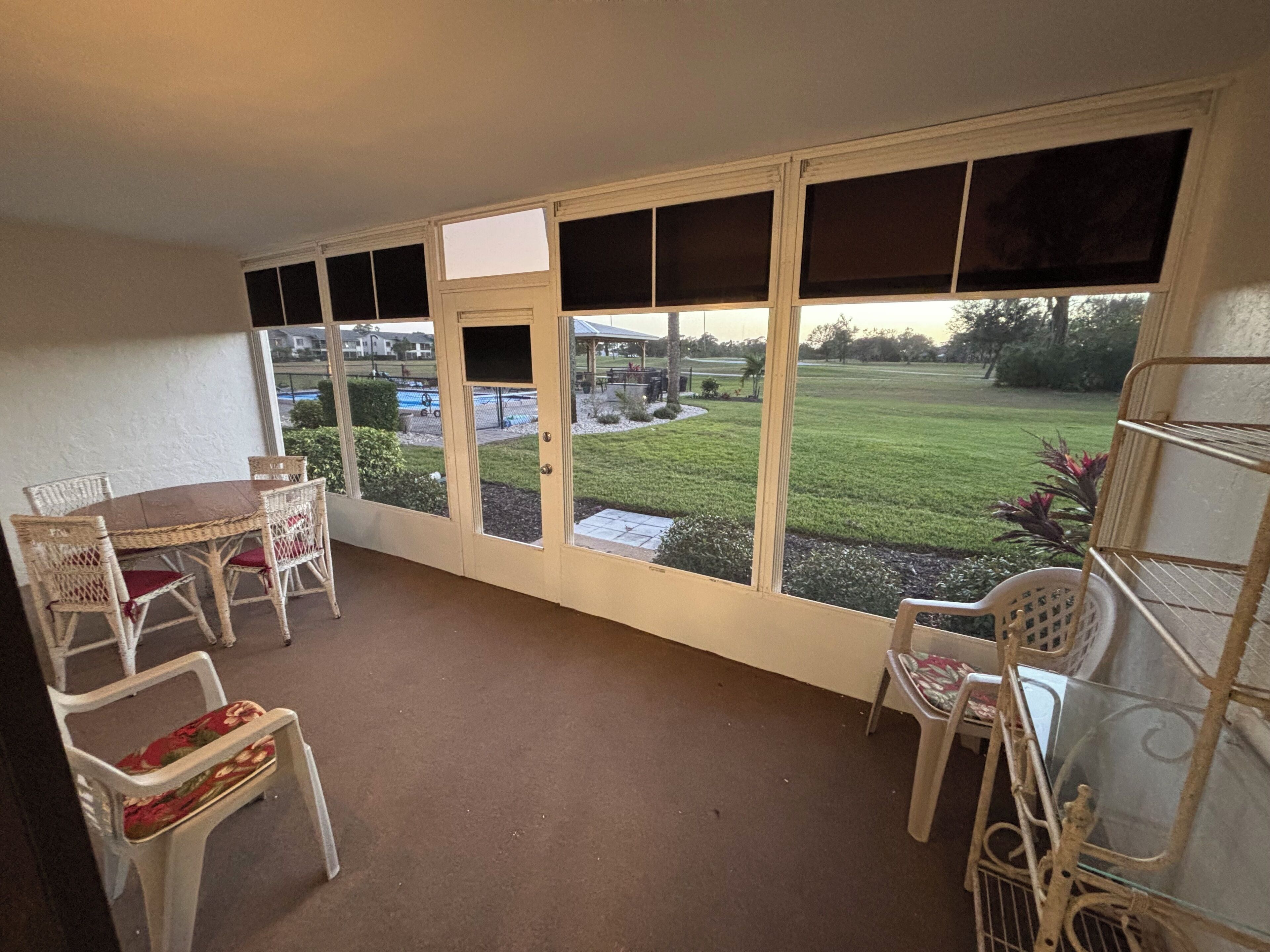Ein Zimmer mit großem Fenster, einem Tisch mit Stühlen und einem kleinen Garten, der sich draußen befindet.