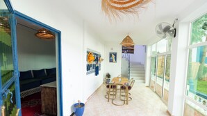 A spacious room with a dining area, a staircase, and large windows.