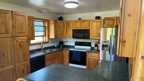 A kitchen with wooden cabinets, a microwave, a stove, a dishwasher, and a refrigerator. - National Forest, Fishing, Trail riding, Hunting, Bars/Eatery and Pet-Friendly (Gilman)